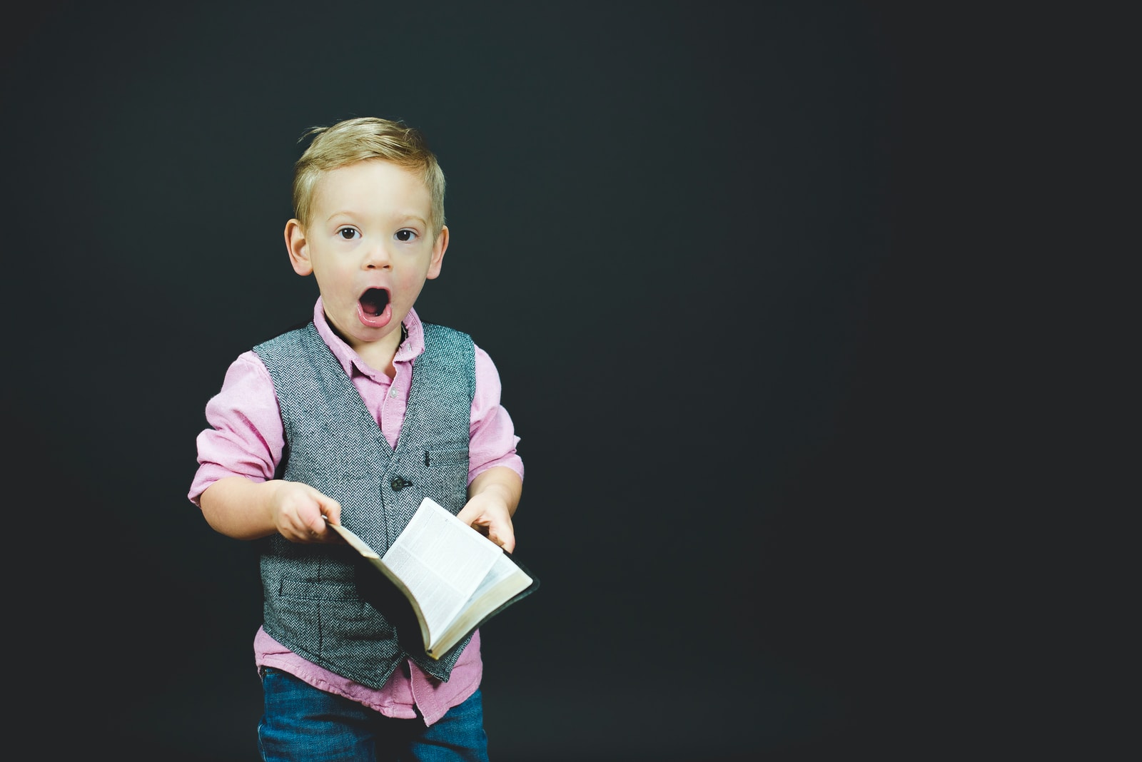Photo by Ben White boy wearing gray vest and pink dress shirt holding book
